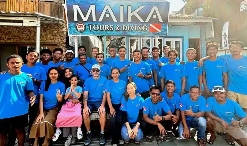 Groupe de personnes souriantes devant la facade d'un centre de plongée