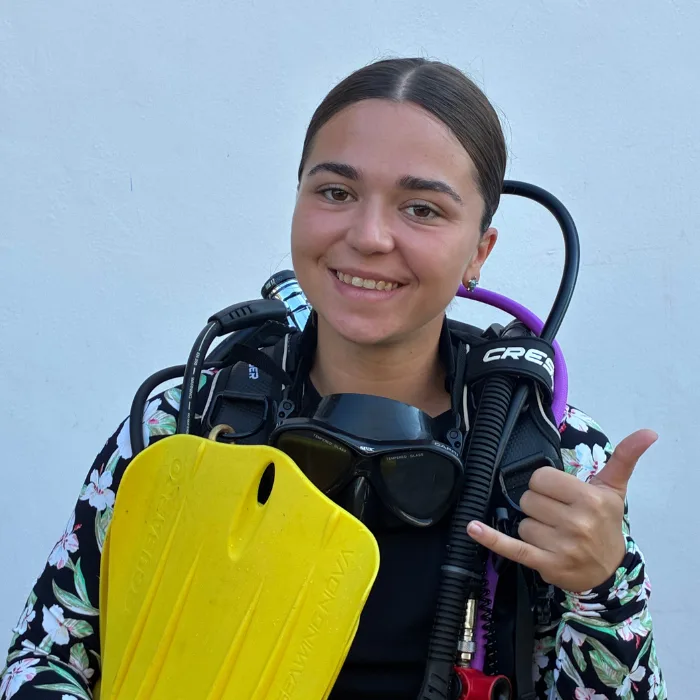 Jeune femme souriante en combinaison de plongée avec palmes jaunes