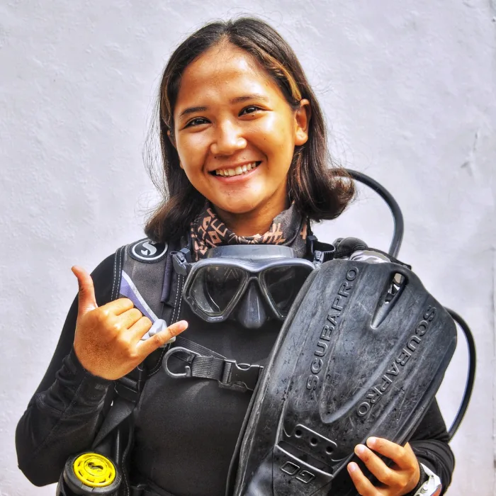 Jeune femme souriante tenant du matériel de plongée Scubapro