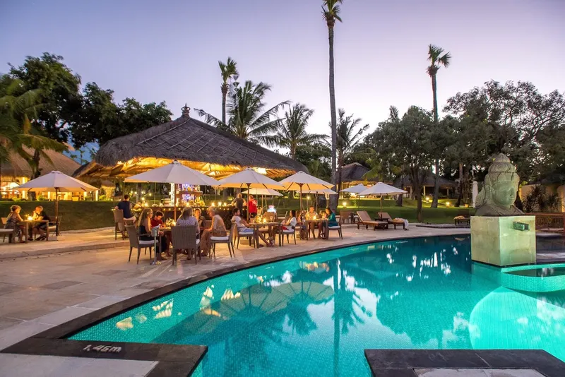 Terrasse avec piscine et personnes assises, ambiance tropicale et relaxante