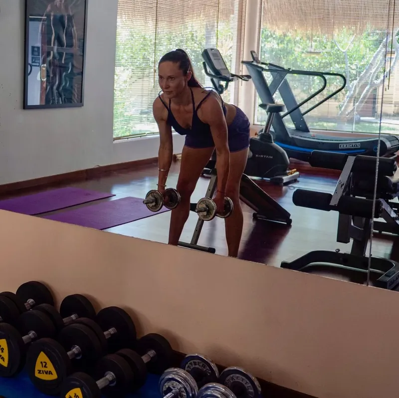 Femme faisant de l'exercice avec des haltères dans une salle de sport