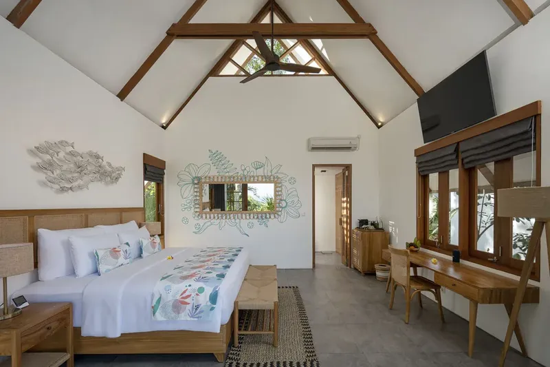 Chambre lumineuse avec lit fait, bureau en bois et décoration florale