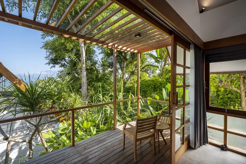 Terrasse en bois avec mobilier, vue sur végétation et mer