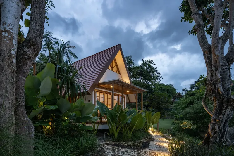 Petite maison avec toit pointu, végétation luxuriante, éclairage doux