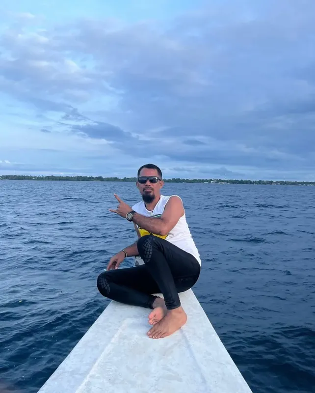 Homme souriant sur la proue d'un bateau en mer calme