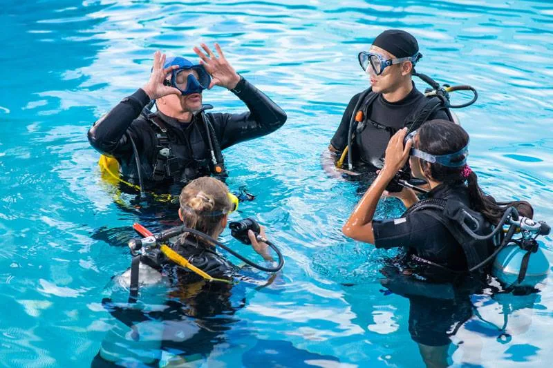Trois plongeurs en formation, communication gestuelle sous l'eau, piscine