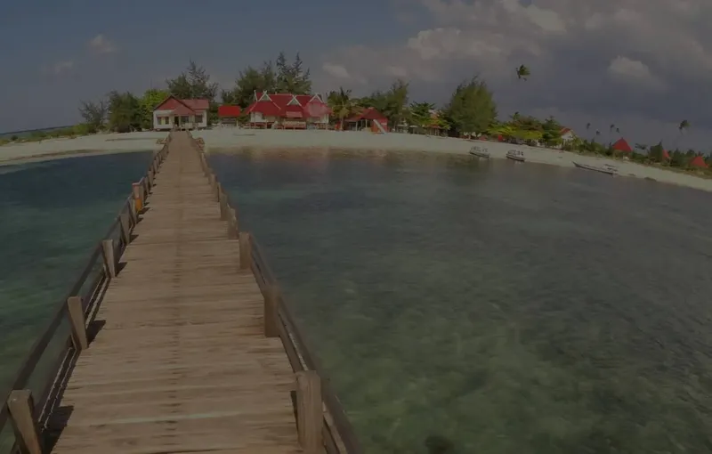 Vue d'un ponton en bois menant à des bâtiments sur une plage