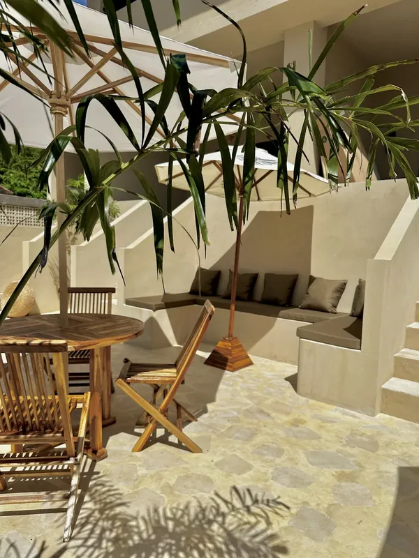 Terrasse ombragée avec mobilier en bois et coussins verts relaxants