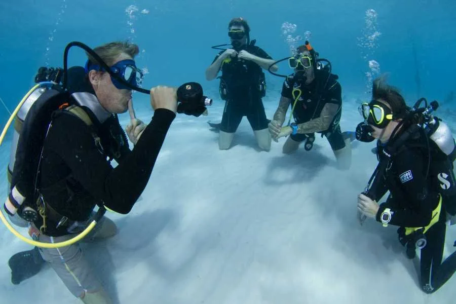 Quatre plongeurs en formation communiquent sous l'eau avec leurs équipements