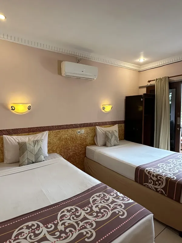 Chambre d'hôtel avec deux lits simples, climatisation et décoration murale