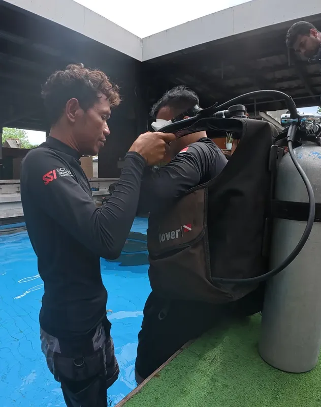 Deux plongeurs vérifient l'équipement près d'une piscine bleue