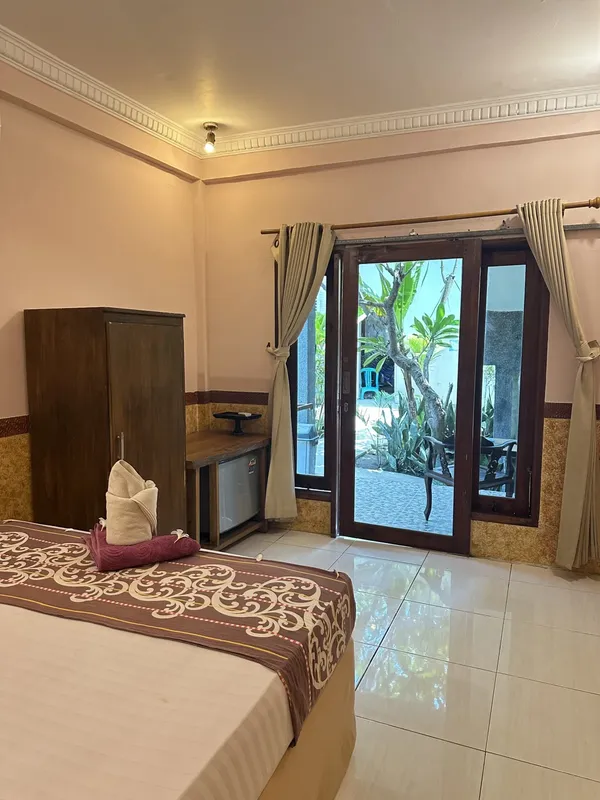 Chambre d'hôtel avec lit décoré, bureau et porte fenêtre ouverte