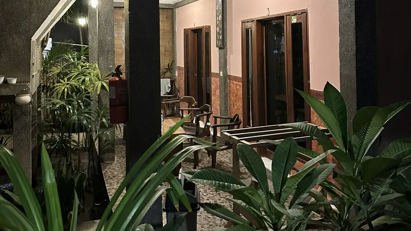 Cour intérieure avec végétation, mobilier et portes ouvertes éclairées