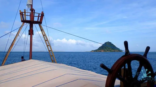Vue depuis un bateau en mer vers une île verdoyante et un ciel bleu