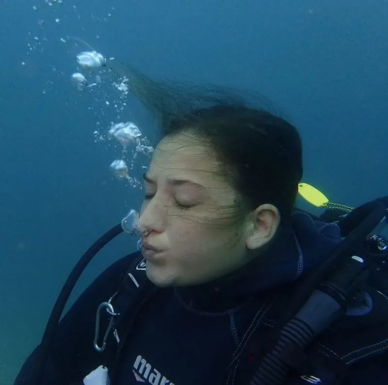 Plongeuse les yeux fermés, cheveux flottants, en équilibre sous l'eau