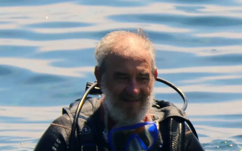 Plongeur souriant avec équipement, visage visible au-dessus de l'eau