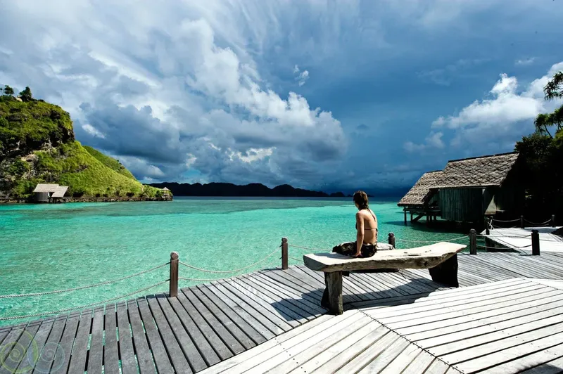 Une personne assise sur un banc en bois face à la mer