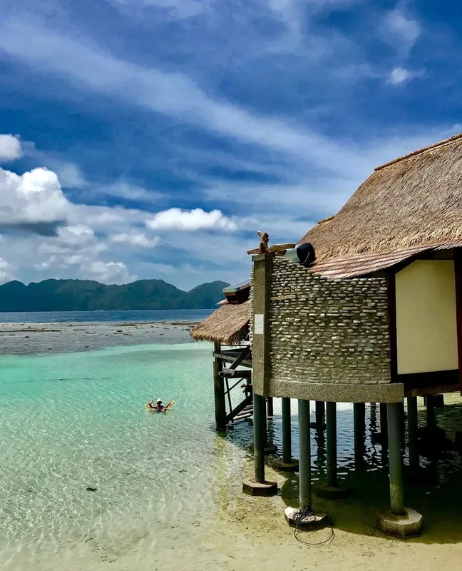Cabanes sur pilotis au bord d'une eau turquoise et d'une plage