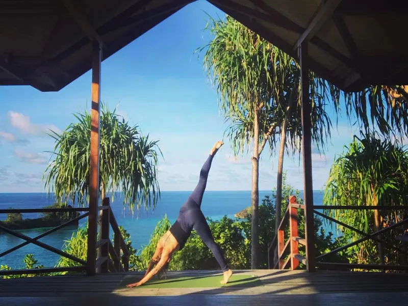 Femme pratiquant le yoga sur une terrasse avec vue sur la mer