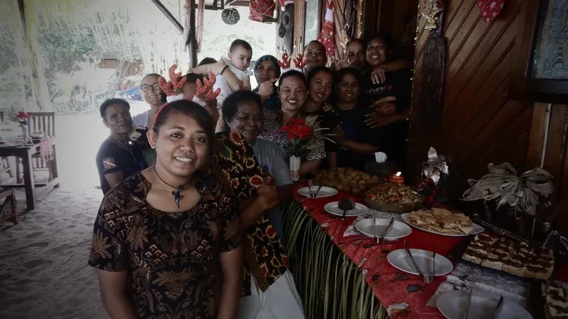 Groupe de personnes souriantes devant une table de nourriture festive