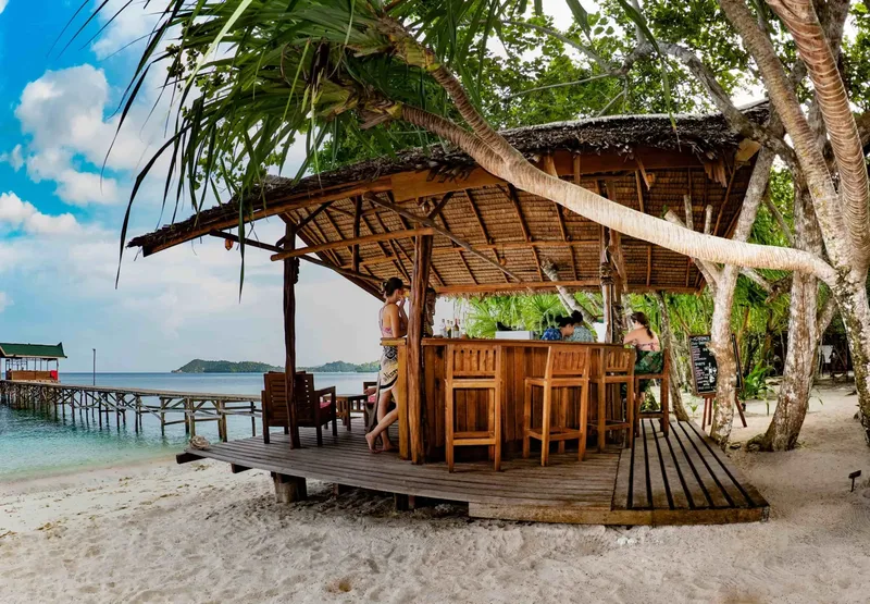 Bar de plage en bois avec des clients et une vue sur la mer