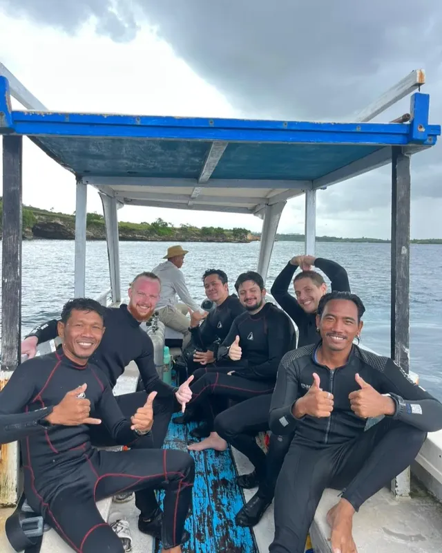 Groupe de plongeurs souriants à bord d'un bateau bleu et blanc