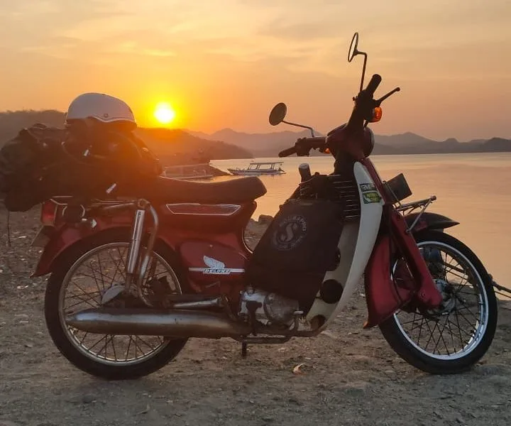 Moto rouge vintage sur une plage au coucher du soleil