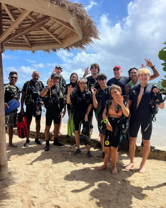 Groupe de plongeurs souriants équipés sur une plage ensoleillée