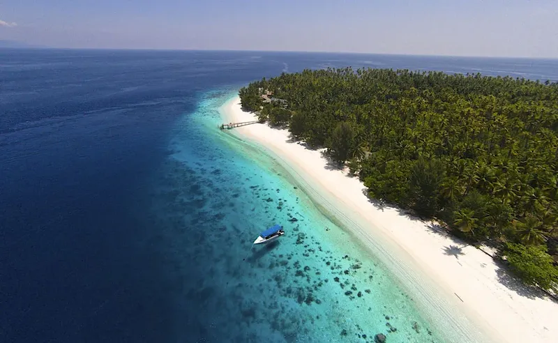 Île tropicale avec plage de sable blanc et bateau en mer turquoise