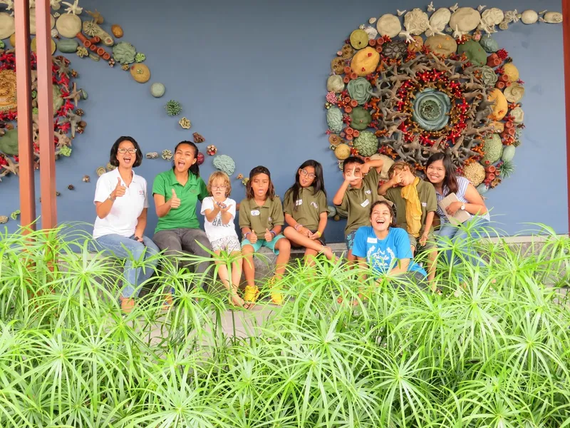 Groupe d'enfants et d'adultes souriants posent devant un mur décoratif