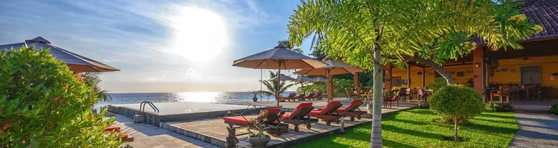 Terrasse avec transats, piscine et végétation luxuriante face à la mer