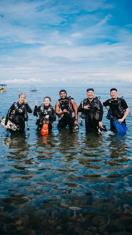 Groupe de plongeurs souriants dans l'eau, équipés et prêts à plonger