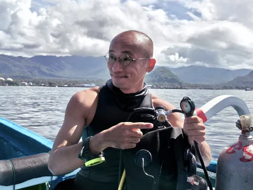 Plongeur souriant sur un bateau, vérifiant son équipement de plongée
