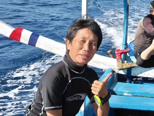 Homme souriant sur un bateau de plongée en mer, pouce levé