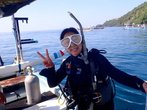 Plongeuse souriante sur un bateau, signe de la victoire