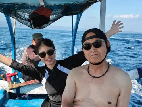 Deux personnes souriantes sur un bateau en mer, journée ensoleillée