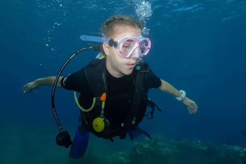 Plongeuse souriante en pleine eau, équipée d'un masque et d'un gilet