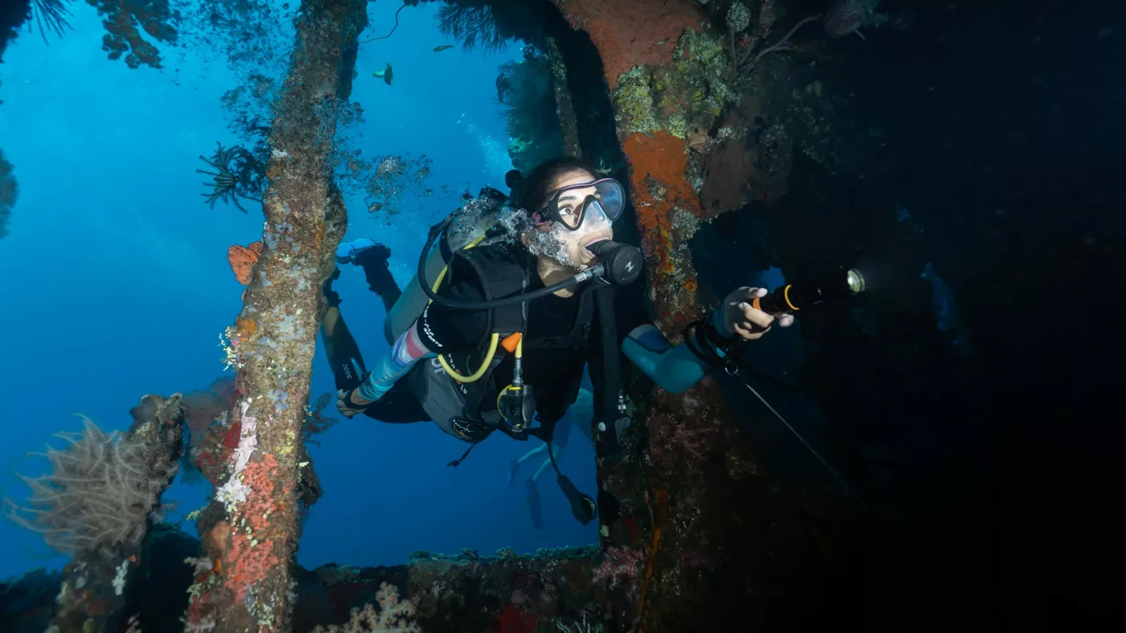 Plongeur explore une épave sous-marine avec une lampe torche