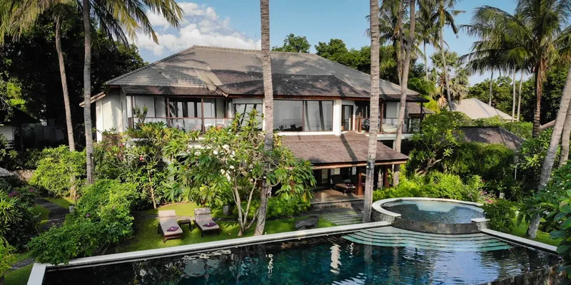 Grande maison blanche avec piscine et végétation tropicale luxuriante