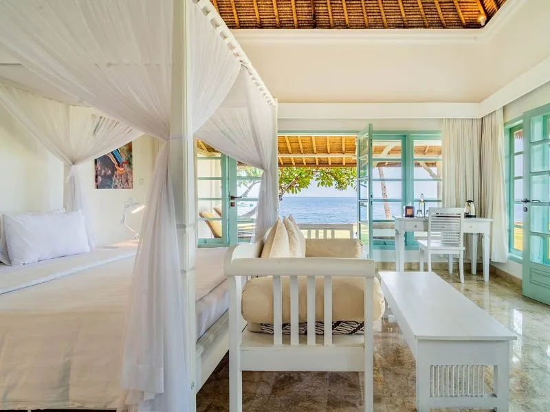 Chambre lumineuse avec vue sur la mer, mobilier blanc et décoration tropicale