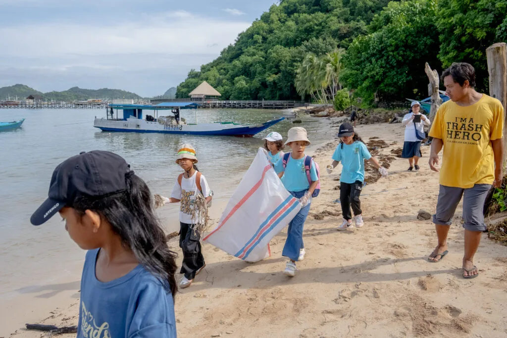 Groupe d'enfants et d'adultes ramassant des déchets sur une plage