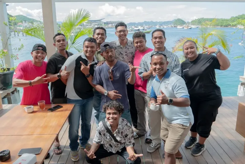 Groupe de personnes souriantes posant devant la mer et des bateaux
