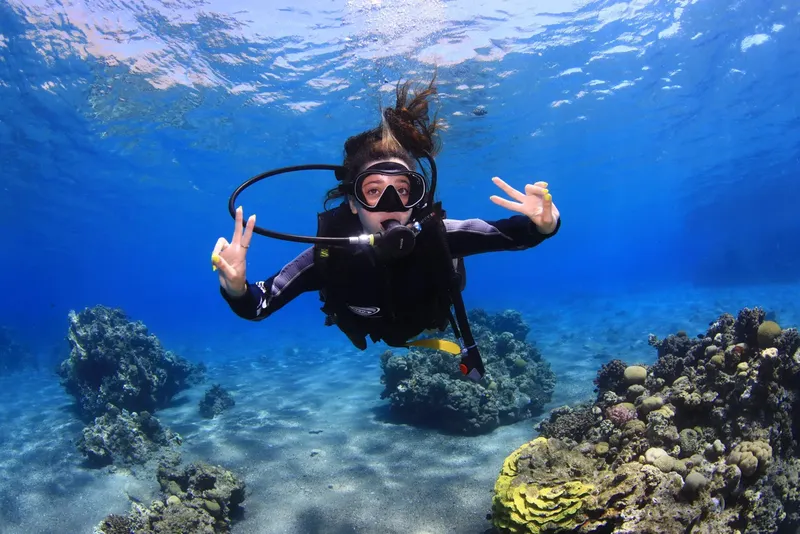 Plongeuse souriante faisant un signe de la main sous l'eau
