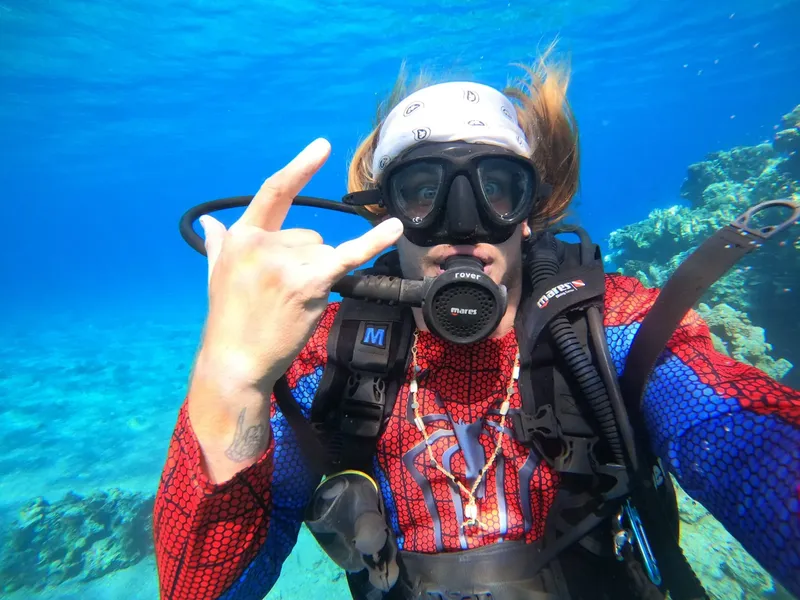 Plongeur souriant avec signe de la main sous l'eau bleue
