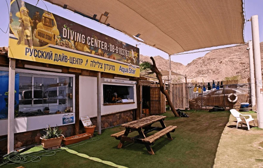 Façade d'un centre de plongée avec une zone de repos et des tables