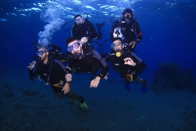 Groupe de plongeurs souriants, équipés, en pleine exploration sous-marine