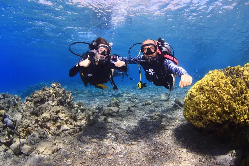 Deux plongeurs souriants font un signe de validation sous l'eau