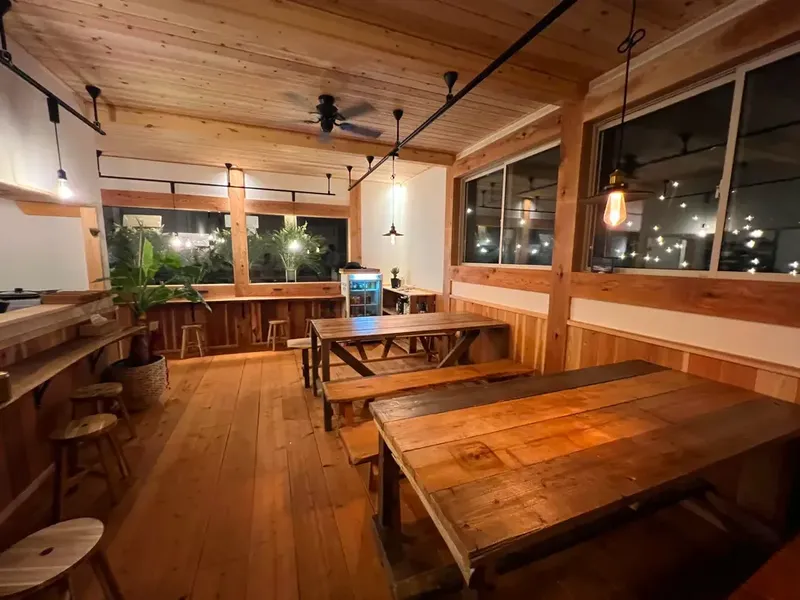 Salle de détente en bois avec tables, chaises et éclairage chaleureux