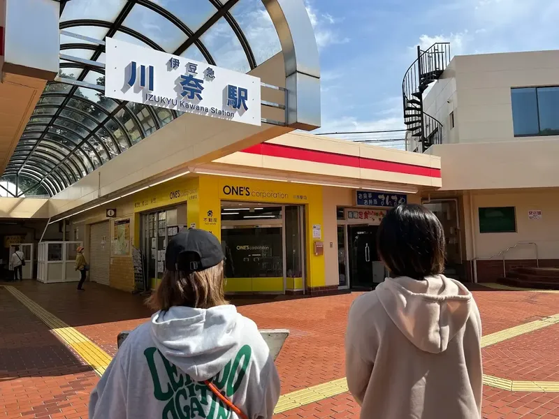 Deux personnes se tiennent dos à la caméra devant une gare
