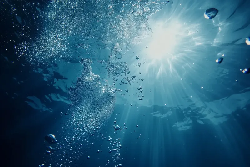 Lumière du soleil filtrant à travers l'eau bleue avec des bulles